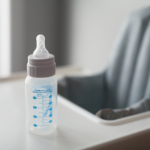 A bottle sitting on the table of a baby chair.