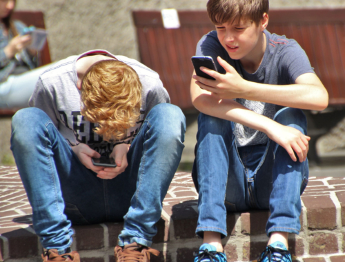 Two teenage boys look at their mobile phones