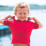 Boy in a red shirt flexing his arms