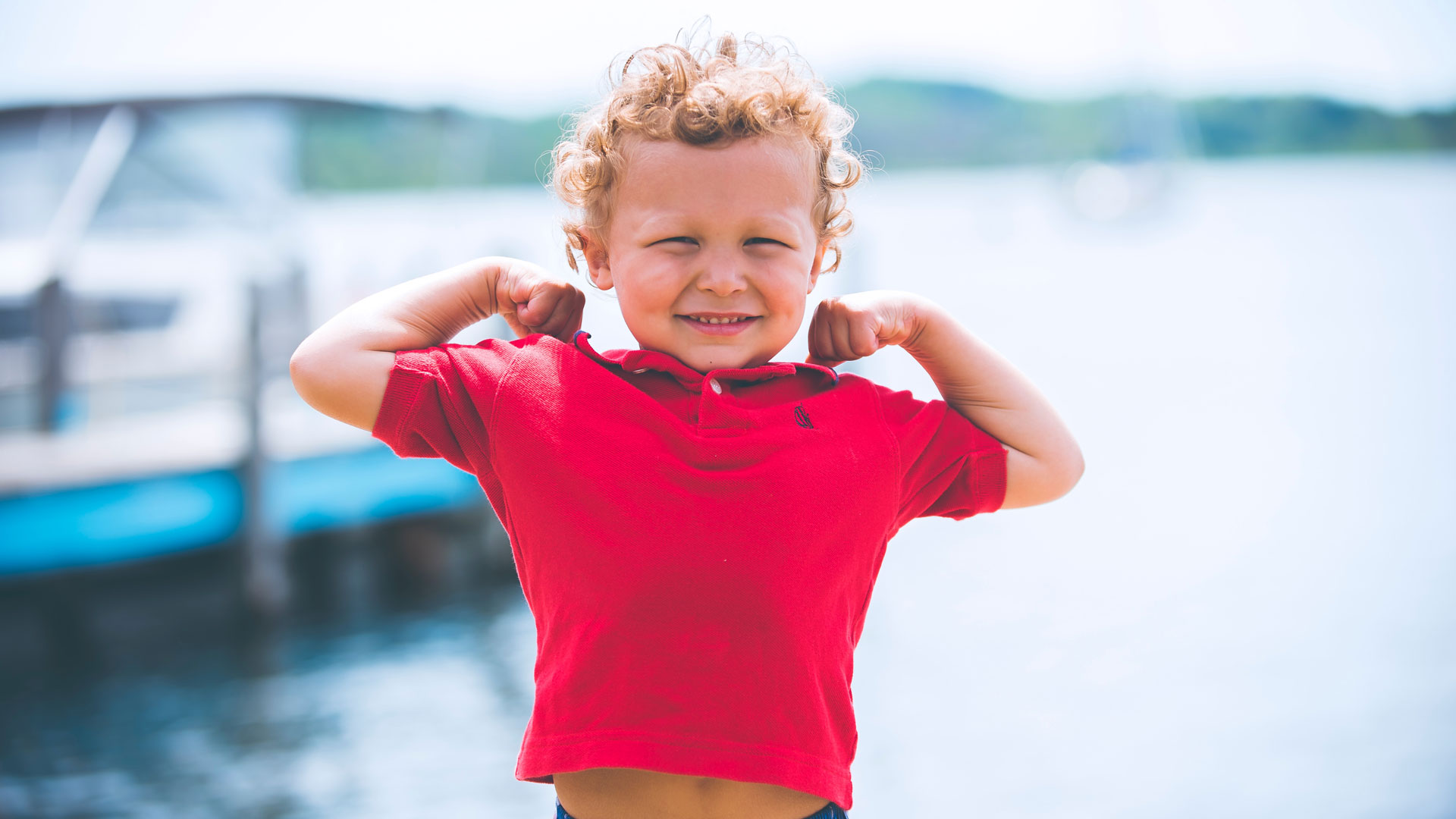 Boy in a red shirt flexing his arms