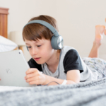 child-on-bed-on-ipad-and-headphones2160