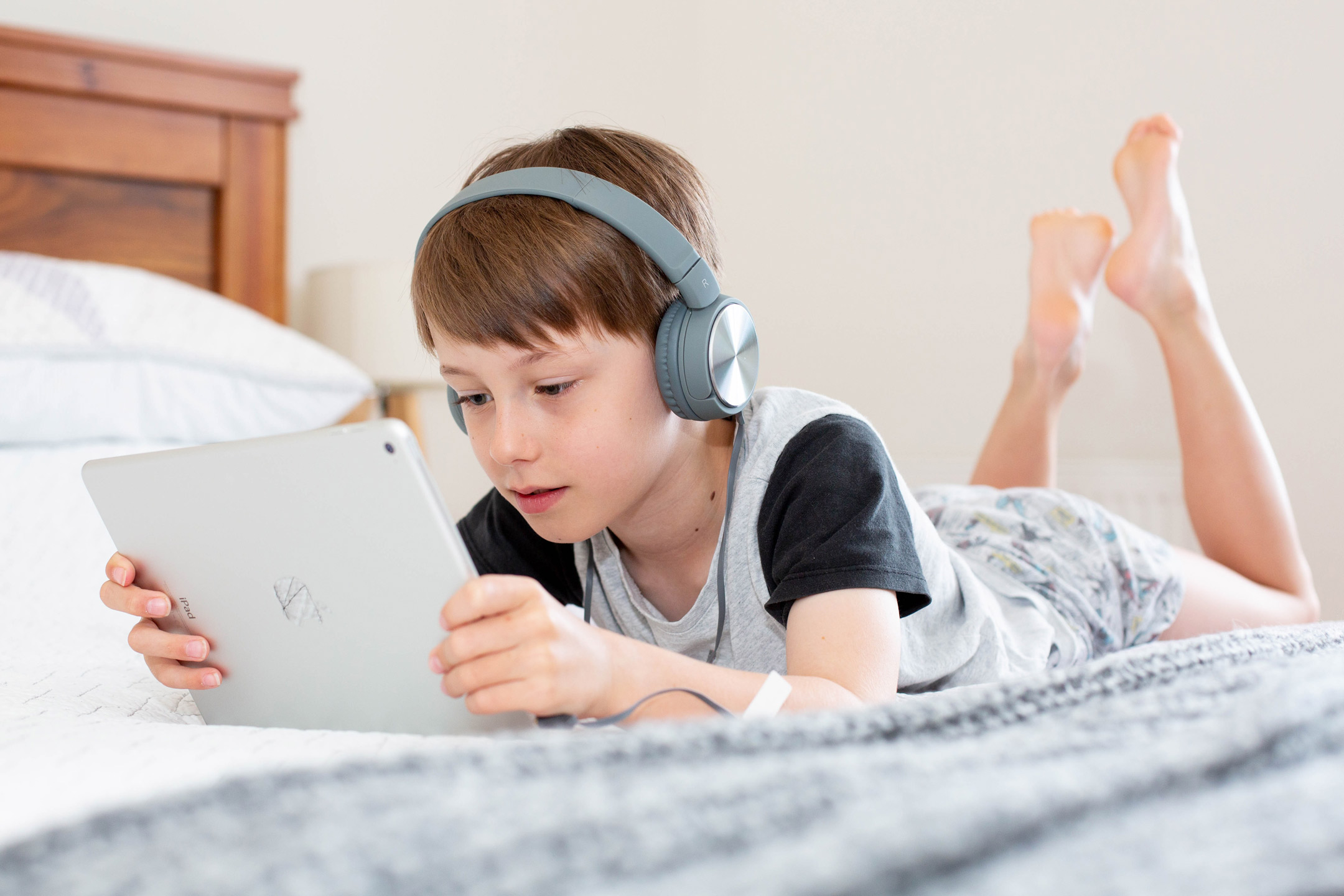 child-on-bed-on-ipad-and-headphones2160